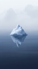 Large iceberg floating on calm water reflecting in the ocean on a foggy day