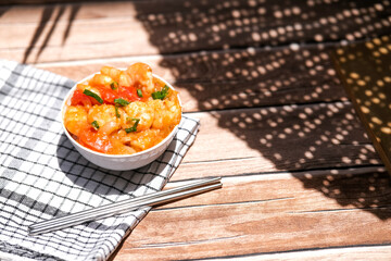 Udang asam manis or sweet and sour shrimp. one of chinese cuisine, shrimp is cooked with garlick, leek, chilli and a sweet and sour sauce added to the white bowl before serving.