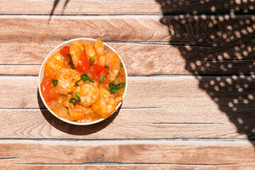 Udang asam manis or sweet and sour shrimp. one of chinese cuisine, shrimp is cooked with garlick, leek, chilli and a sweet and sour sauce added to the white bowl before serving.