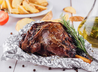 Roasted lamb leg with rosemary and spices on white table