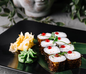 Delicious sushi rolls being served on black plate for dinner