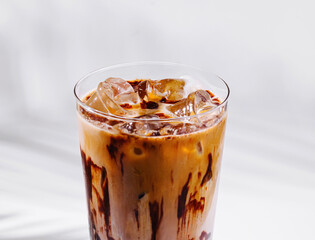 Iced coffee with chocolate syrup drizzled on the glass standing on white background