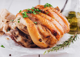 Crispy pork knuckle with rosemary and spices on white table