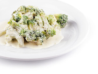 Steamed broccoli florets covered with creamy cheese sauce on white plate