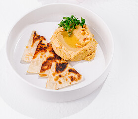 Hummus topped with pine nuts and olive oil served with pita bread and vegetables