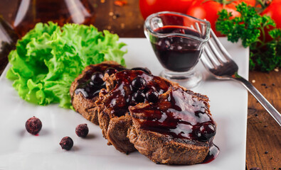 Grilled beef medallions covered in blueberry sauce with fresh greens