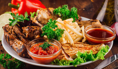 Grilled meat plate served with french fries and dipping sauces