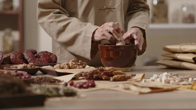 Video template in the setting of a traditional medicine room, cloves are put into a brown mortar by the herbalist and then crushed in a wooden pestle.
