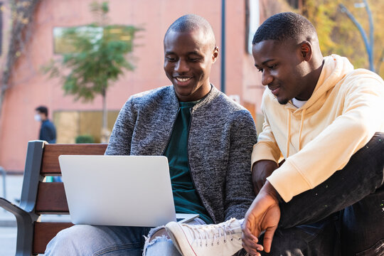 Young black friends using laptop in the street