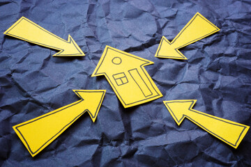 Arrows pointing at a model house. Real estate strategy and housing development.
