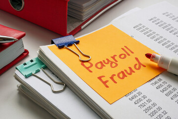 Stack of documents with a note saying payroll fraud.