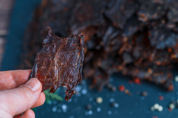 Hand Holding Traditional Beef Jerky Piece, Close-Up Macro View