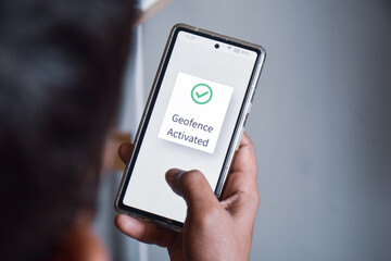 Man hand holding phone. Mobile screen showing he finished geofence activation steps successfully. Selective focus, location based services, virtual perimeter settings concept.
