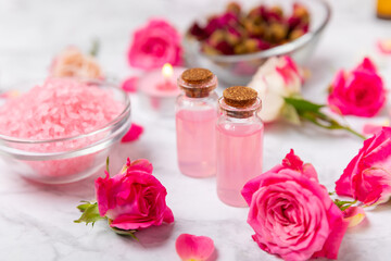 Rose essential oil on a textured background.Roses and a bottle of rose perfumed water.Aromatherapy...