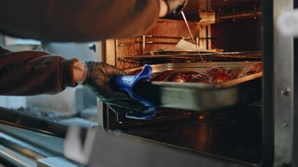 Professional cook baking eggplants in kitchen oven closeup. Unknown chef hands