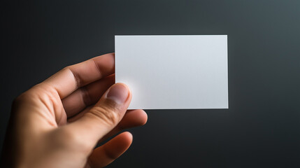 Fototapeta premium Hand Holding Blank White Business Card Against Dark Background