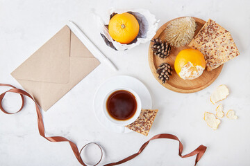 Christmas background. Festive envelope, table setting scene with coffee cup, tangerines among decorations. Copy space.