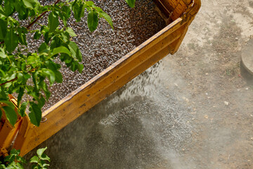 Construction gravel is being dumped from a truck bed at a construction site, close-up of gravel...