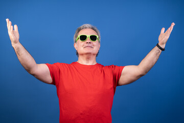 Naklejka premium A man in a red shirt and yellow sunglasses is reaching up with his hands