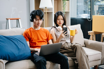 Smiling couple enjoying casual moments on the couch with a laptop, showcasing teamwork, laughter, and a relaxed