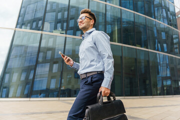 Businessman Walking Confidently Outside a Modern Office Building While Checking His Phone During the Afternoon