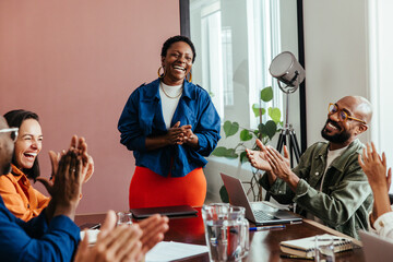 Team celebrates achievement with praise and applause in conference room