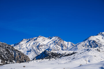 Winter landscape with mountains covered snow under a blue sky in cold sunny day