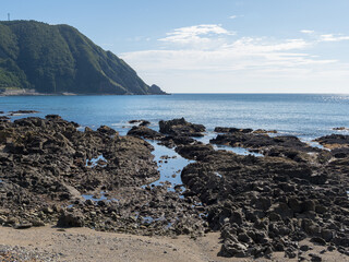 快晴の下の岩の海岸と遠くに見える水平線