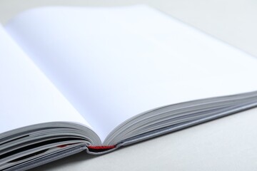 Open book with hard cover on light grey table, closeup