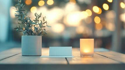 serene table setting featuring small potted plant, lit candle, and blank thank you card, creating warm and inviting atmosphere for charity event