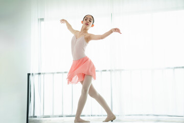 Teenage ballerina practices her stretching routine in studio before practicing ballet, Young dancer warming up in ballet studio, Girl is studying ballet