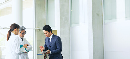 白衣の技術者に説明するビジネスマン