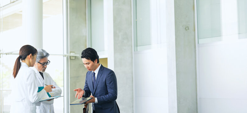 白衣の技術者に説明するビジネスマン