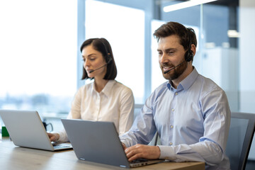 Customer service representatives using laptops and headsets engaged in professional work environment. Focused individuals collaborating and communicating effectively.