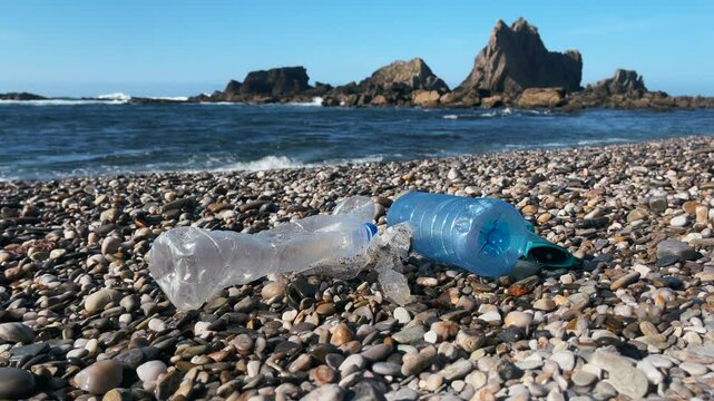 Trash plastic bottles and caps on a pebble beach near the ocean