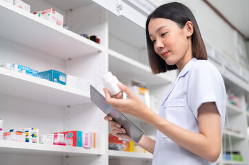 Asian professional female pharmacist using tablet to check drug list Pharmacist checking stock in pharmacy for health medicine in technology pharmacy looking at camera smiling
