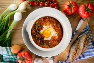Spanish tapa of baked egg with chorizo ​​and tomato. Top view table with  decorations.
