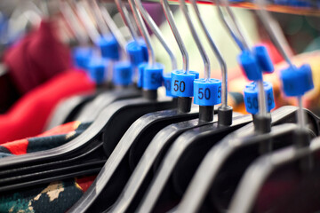 Different sized hanger with colorful dress blue size tags 50 clothes displayed in shop for sale....