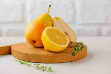 Fresh pear with lemon and thyme on a wooden board.
