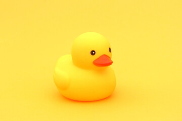 A yellow rubber duck stands on a yellow background.