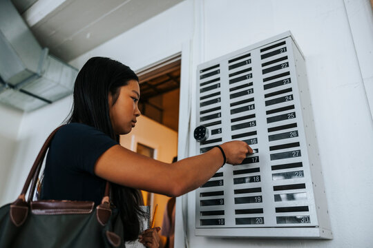 Low angle view of junior high student keeping smart phone in locker at school