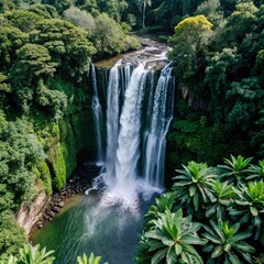 Naklejka premium A powerful aerial shot of a waterfall cascading through dense, lush jungle vegetation. The bright green leaves contrast with the white spray of the water, creating a dynamic and untouched natural scen