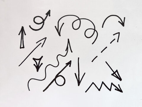A collection of black arrow shapes and abstract lines arranged on a white surface, illustrating movement and direction