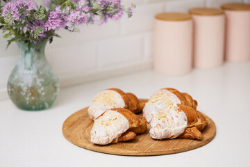 Delicious fresh croissants on wooden tray on white table, closeup