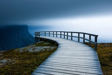 Obraz premium A serene wooden walkway winding through misty landscape, offering a peaceful escape into nature's calm beauty.