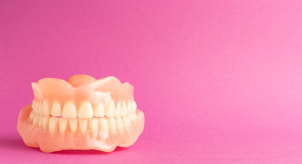 Dentures on a pink background with space for your text or product, health care concept