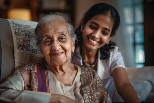 Happy Indian ethnic senior woman sitting in a wheel chair escorted by a care taker