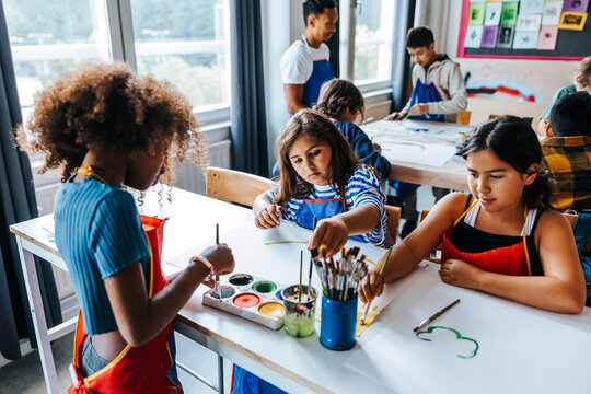Female students painting during art class in elementary school