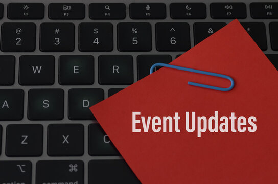 The image depicts a keyboard with a red sticky note attached to it, containing the words "Event Updates."