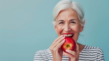 A senior female holding and eating a fresh ripe apple